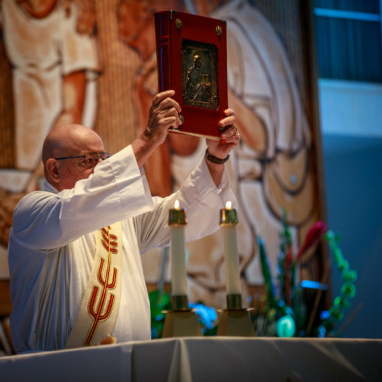 Priest raising the bible in a mass service image