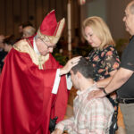 Bishop Noonan invokes the gifts of the Holy Spirit through the laying of hands on Aldo, during Confirmation photo