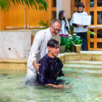 Priest baptizing a young man image